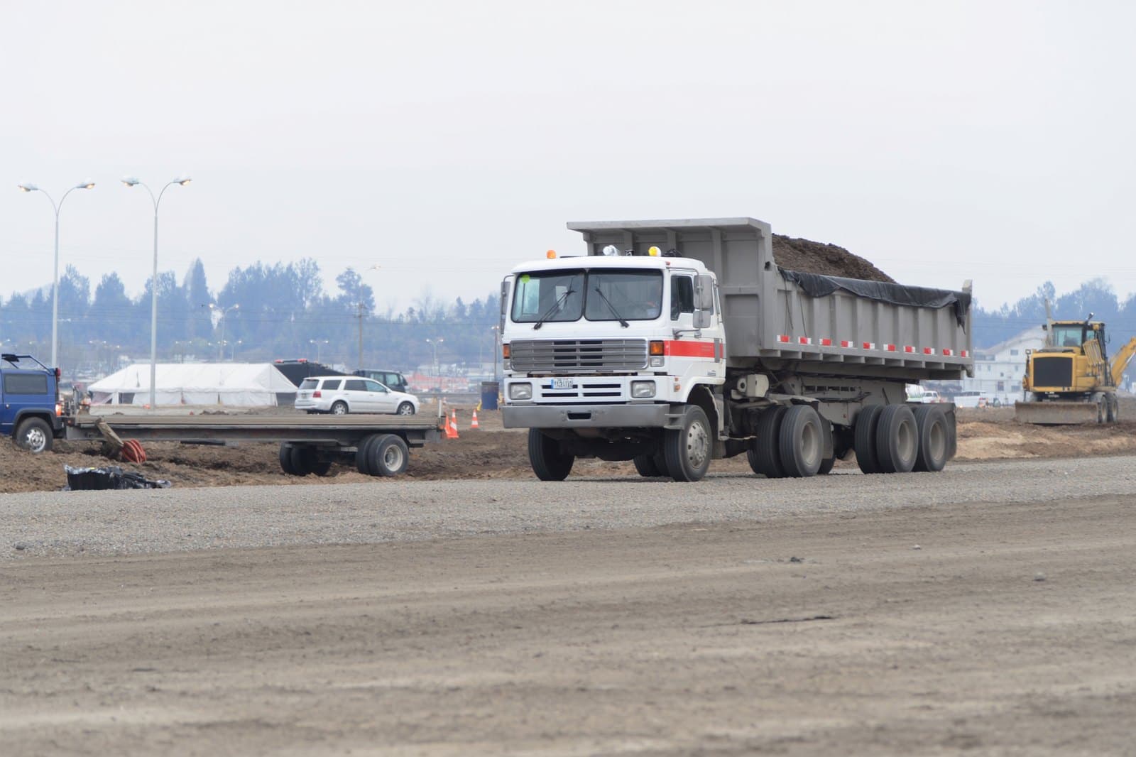 Loaded dump truck on a gravel haul road across a commercial site