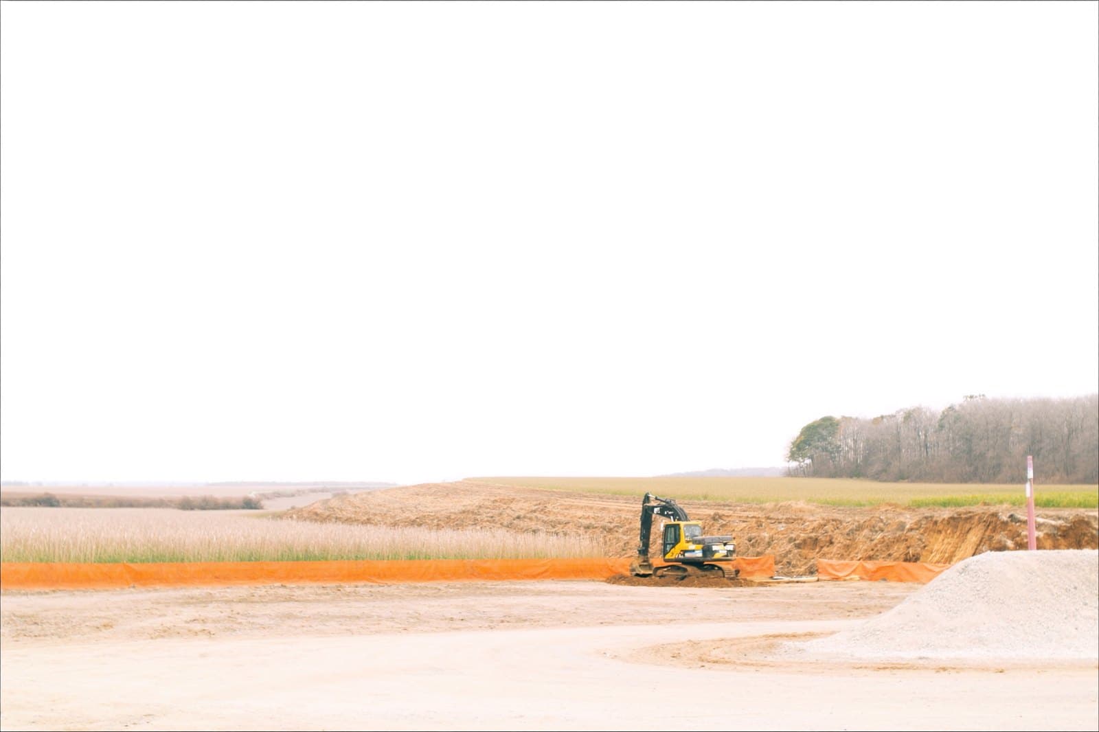 Excavator cutting a building pad behind a silt fence line